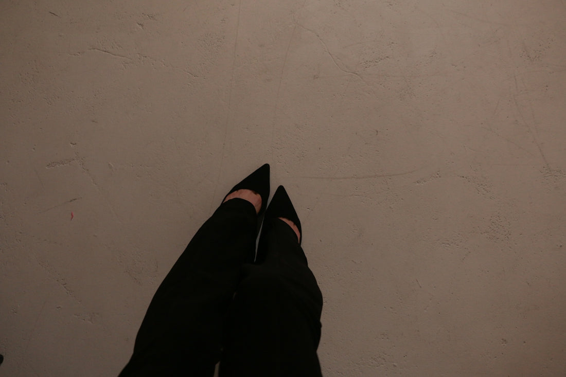 a person wearing black shoes standing in front of a white wall