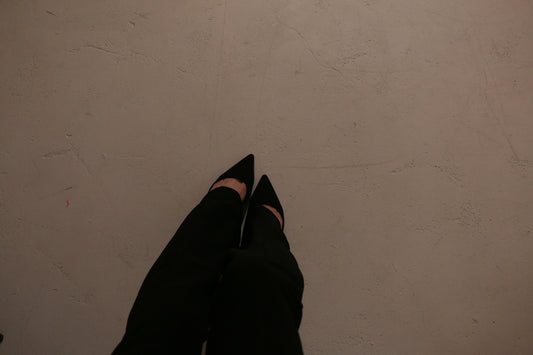 a person wearing black shoes standing in front of a white wall