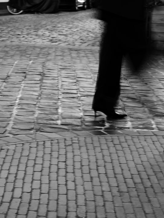 A person walks on cobblestone street.