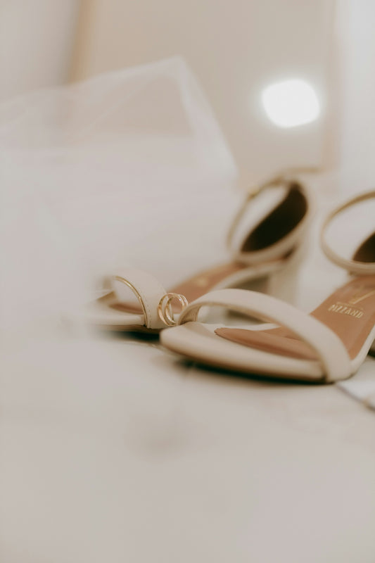 Wedding rings rest on elegant bridal heels.