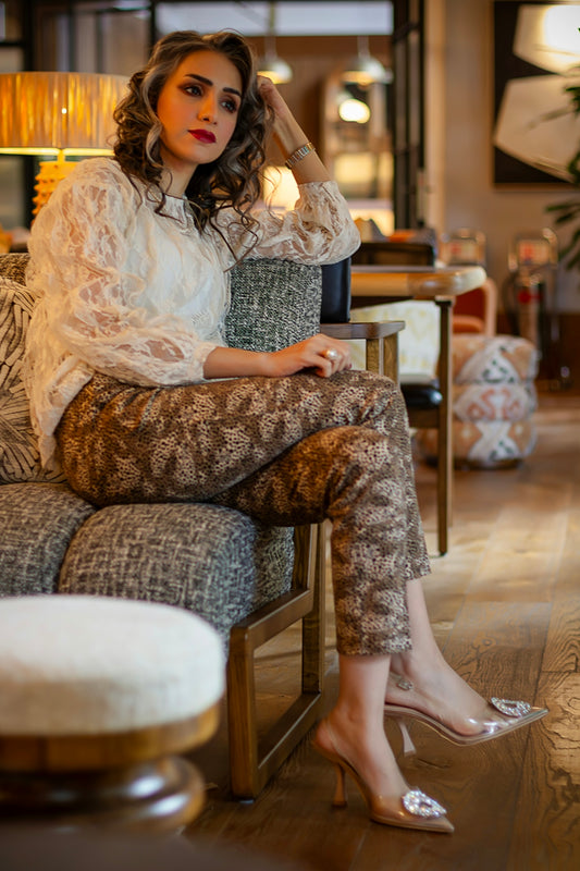 A stylish woman poses elegantly on a sofa.