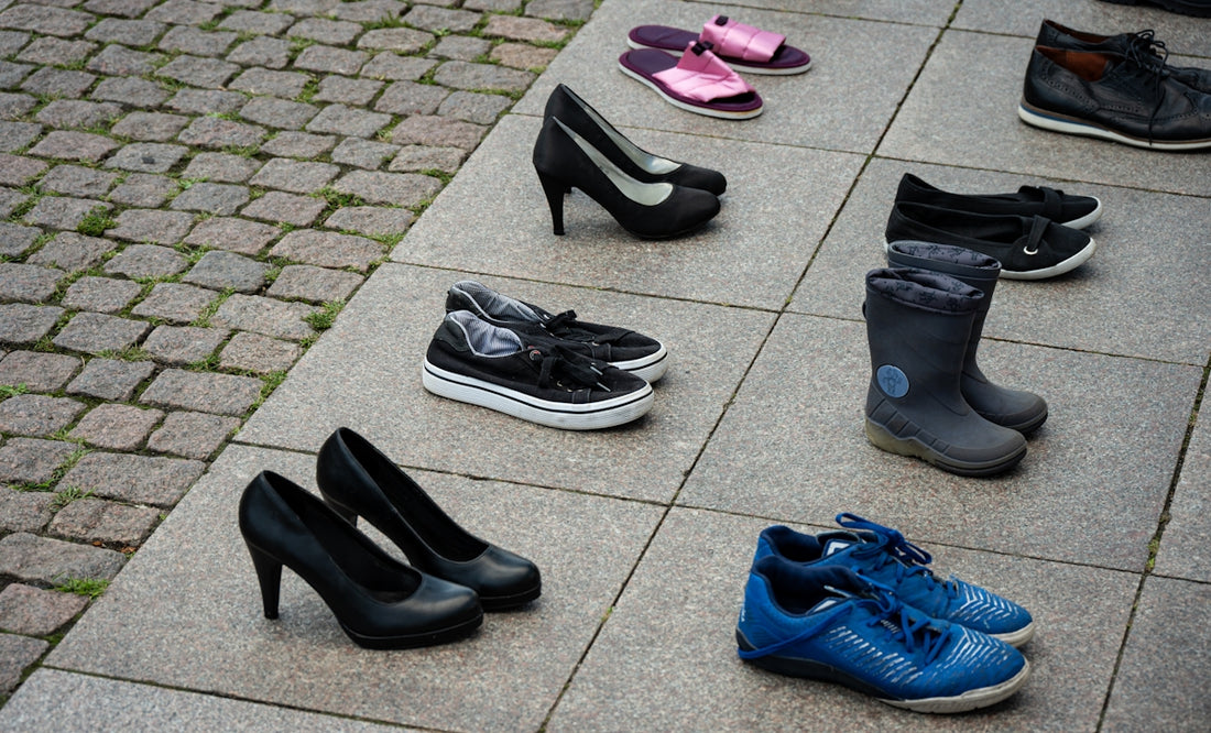 Assortment of shoes arranged on pavement