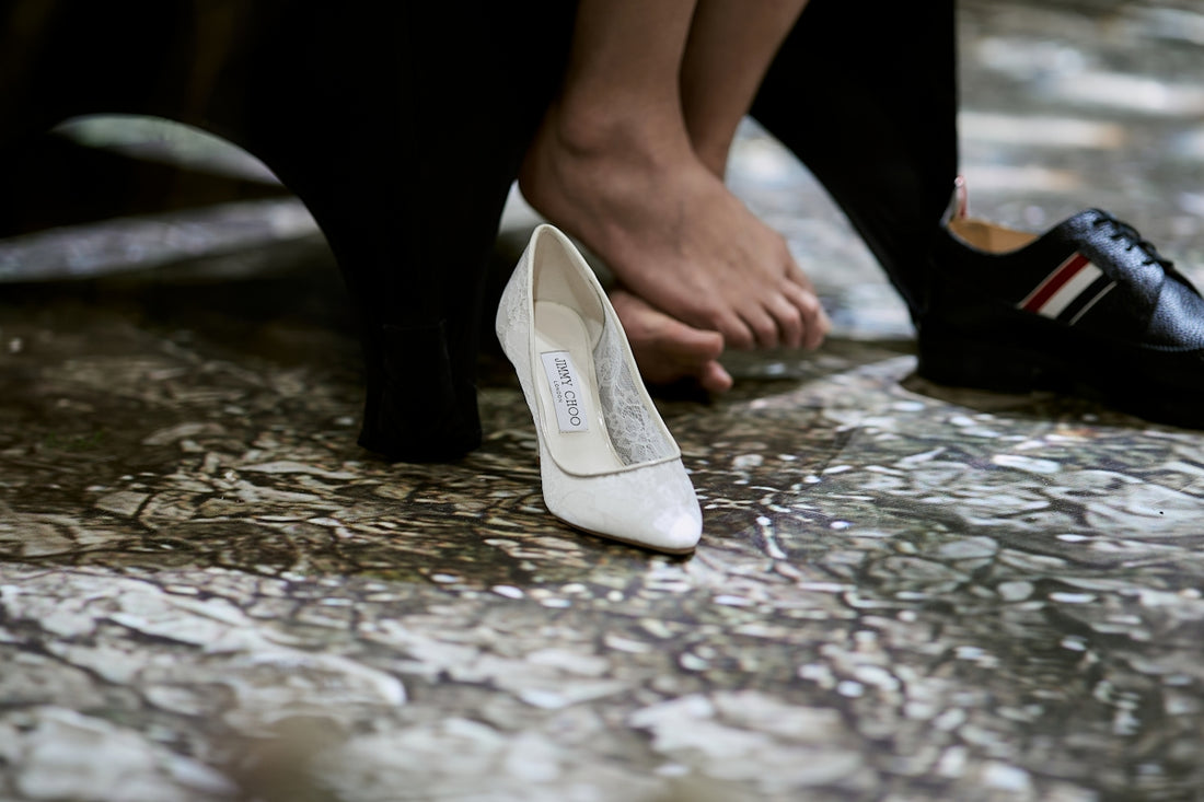 White high heel, bare foot, and black man's dress shoe.