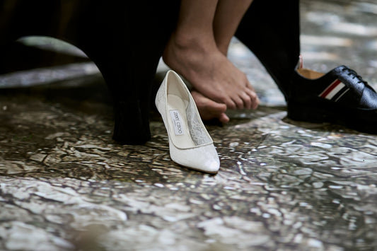 White high heel, bare foot, and black man's dress shoe.